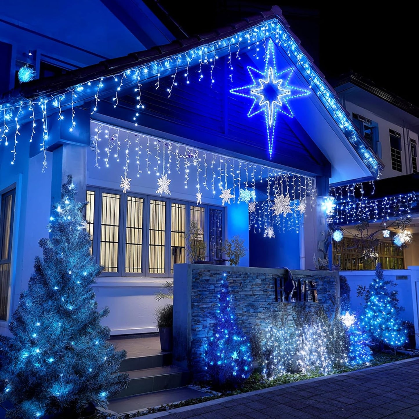 House exterior decorated with blue Christmas lights and stars at night.